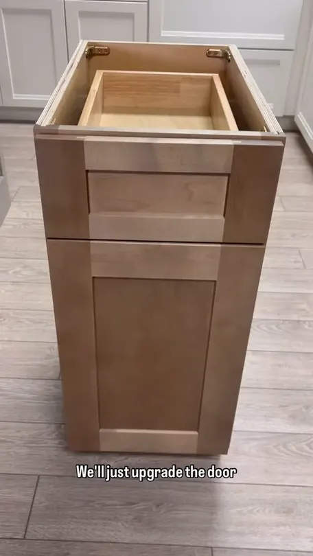A stained solid birch base cabinet standing on the showroom floor, door and drawer front in shot
