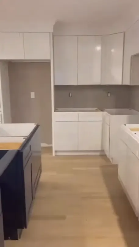 A finished kitchen with a navy island and pale wall cabinets