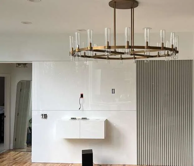 White gloss floating console on a fluted wall with full-height fluted / reeded wall panelling and brass ring chandelier with clear glass candle tubes.