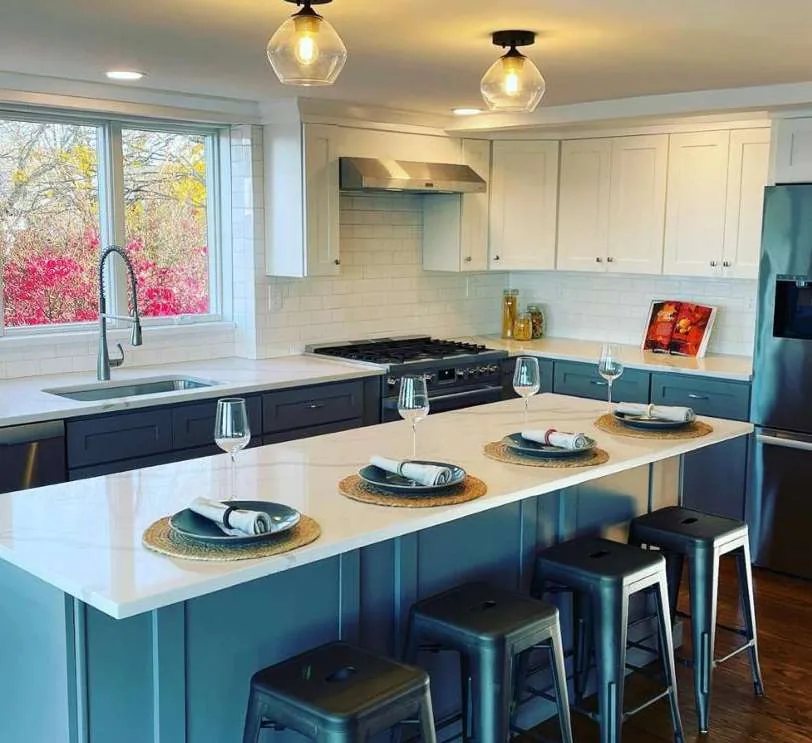 Teal shaker kitchen with a quartz peninsula set for dinner, installed by QDC