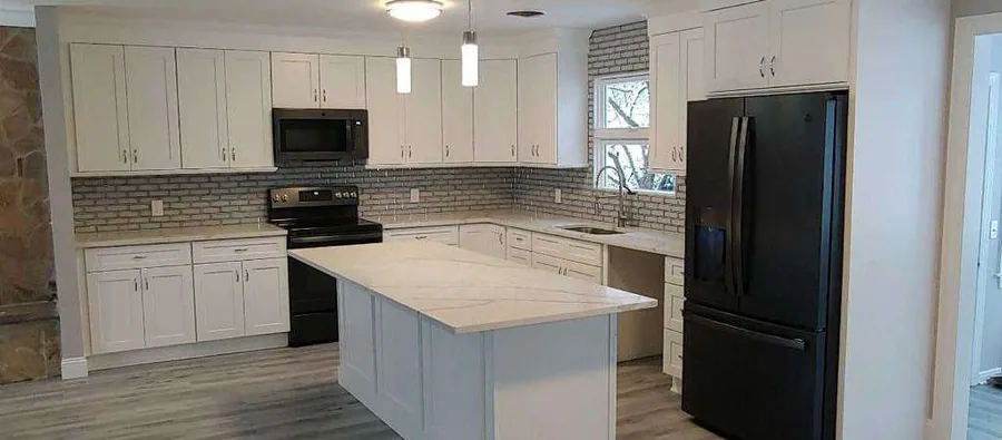 Three walls, two corners, and the most cabinetry of anything on this shelf — the sink under the window on the short wall, the range and the refrigerator facing each other.